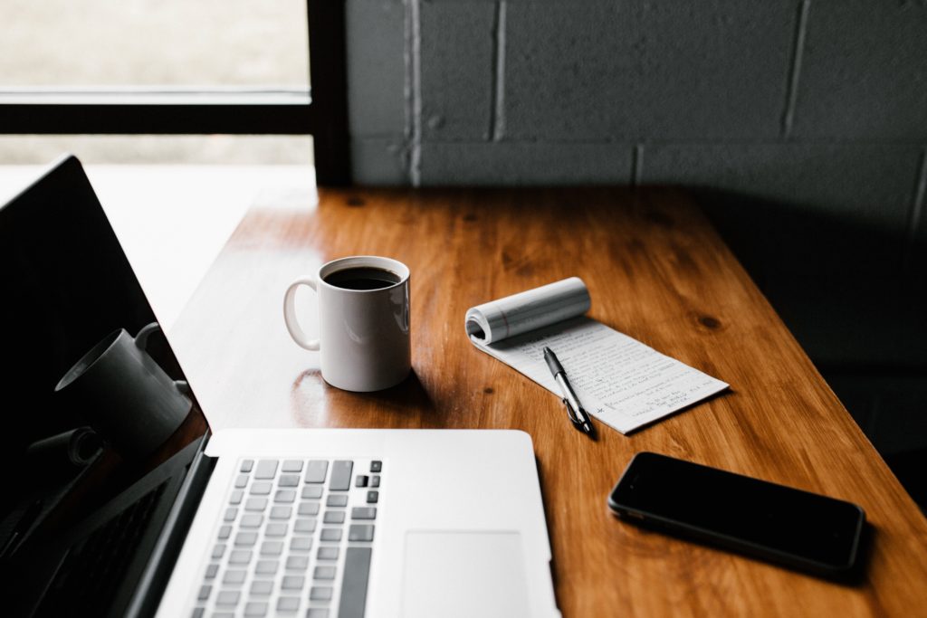 first blog post, computer, notepad, on a wooden table